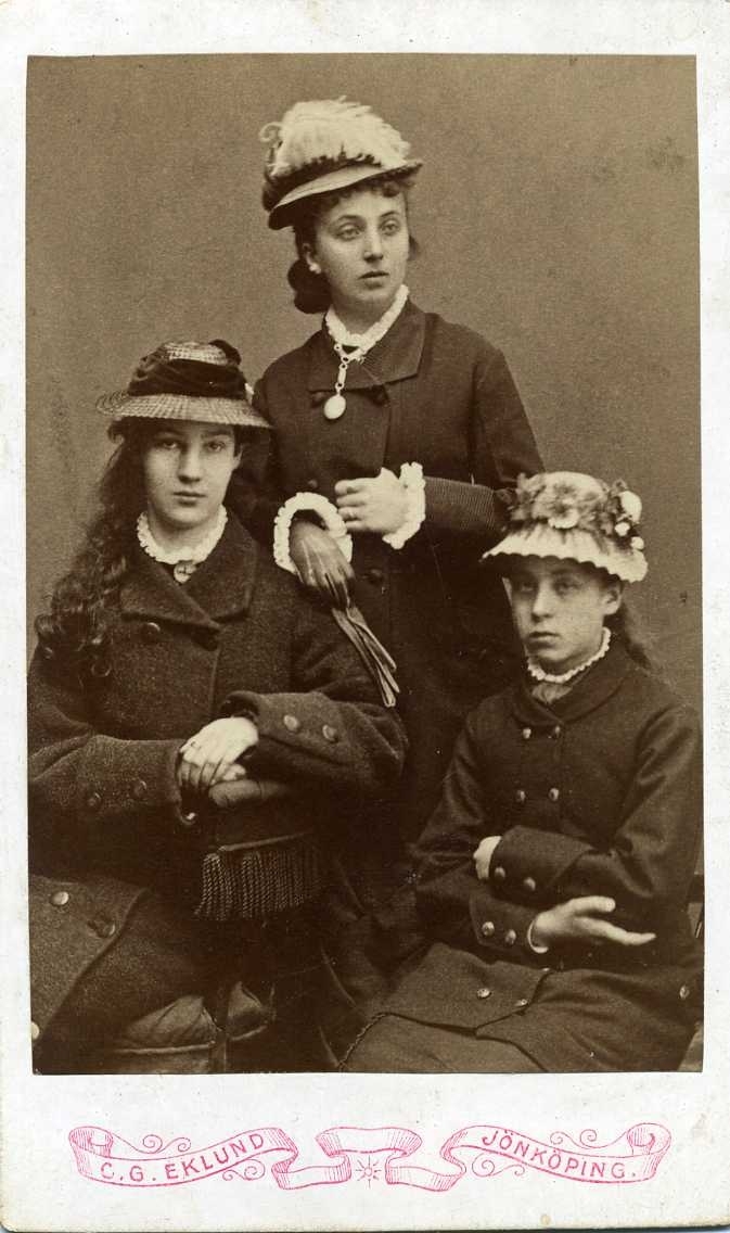 Kabinettsfotografi: Tre unga kvinnor med kappa och hatt: Anna och Agnes Granlund samt en icke identifierad