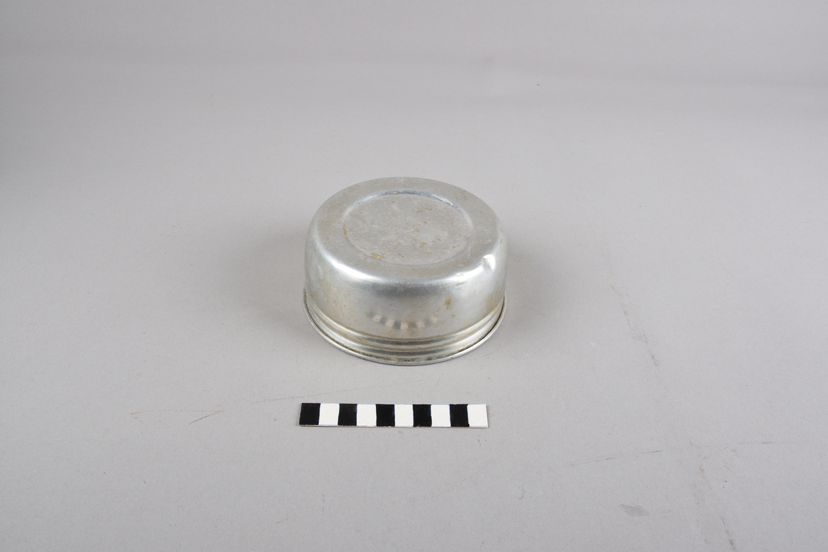 Termos med sylindrisk form og vid opning. Glaskolbe i metallbehaldar. Kork med svakt konisk form, flat på toppen. Toppen dekt av metallflate med profilerte dekorringar. Metallskål med gjengar skruvast på toppen av termosen. Øvst oppe på ytterbehaldaren er det to festeordningar med lærreim trekt gjennom for hank.
