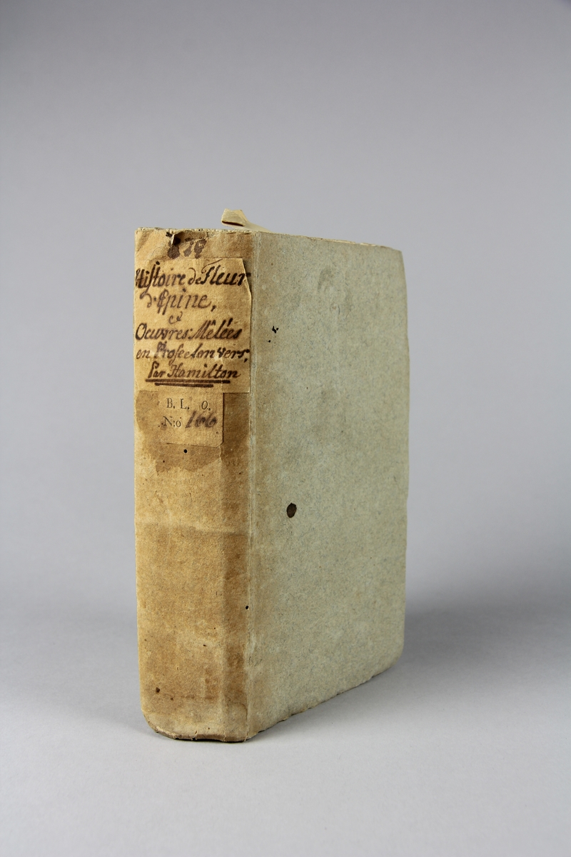 Bok, pappband, "Histoire de Fleur d'Épine, et Oeuvres mêlées en prose et en vers", skriven av Hamilton, tryckt 1749.
Pärm av gråblått papper, oskurna snitt. Blekt rygg med etiketter med titel och samlingsnummer.