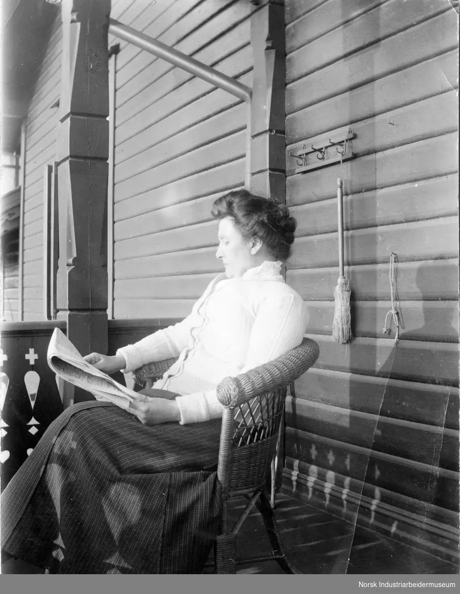 Kvinne leser avisen i kurvstol utendørs.