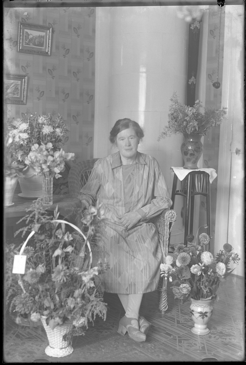 Fru Hallgren fotograferad omgiven av blommor i samband med sin 50årsdag. Tolkat som Hilda Elisabeth Hallgren (f. Kämpe).