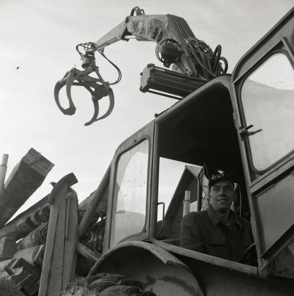 En man sitter i en traktor och har lastat vagnen full med timmerstockar i Rengsjö, 1967.
