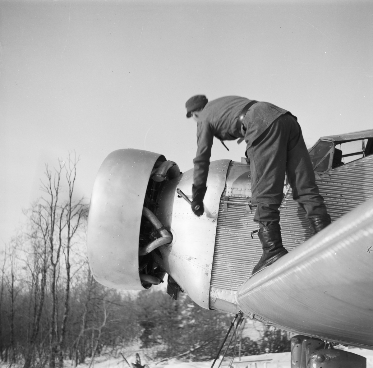 Flygplan Junkers F-13 startas med handvev vid F 19, Svenska frivilligkåren i Finland. En mekaniker står och vevar på vingen på flygplanet.
