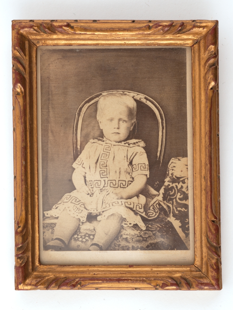 Portrett av liten gutt sittende på stol.