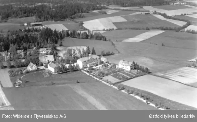 Haugetun ungdomsskole med bolighus bak og mange åkerlapper. Tatt fra Rolvsøysund/ Visterflo.