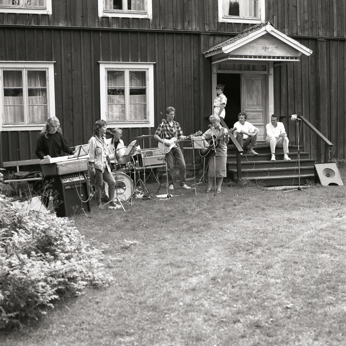 En grupp spelar musik framför ett hus, 1986.