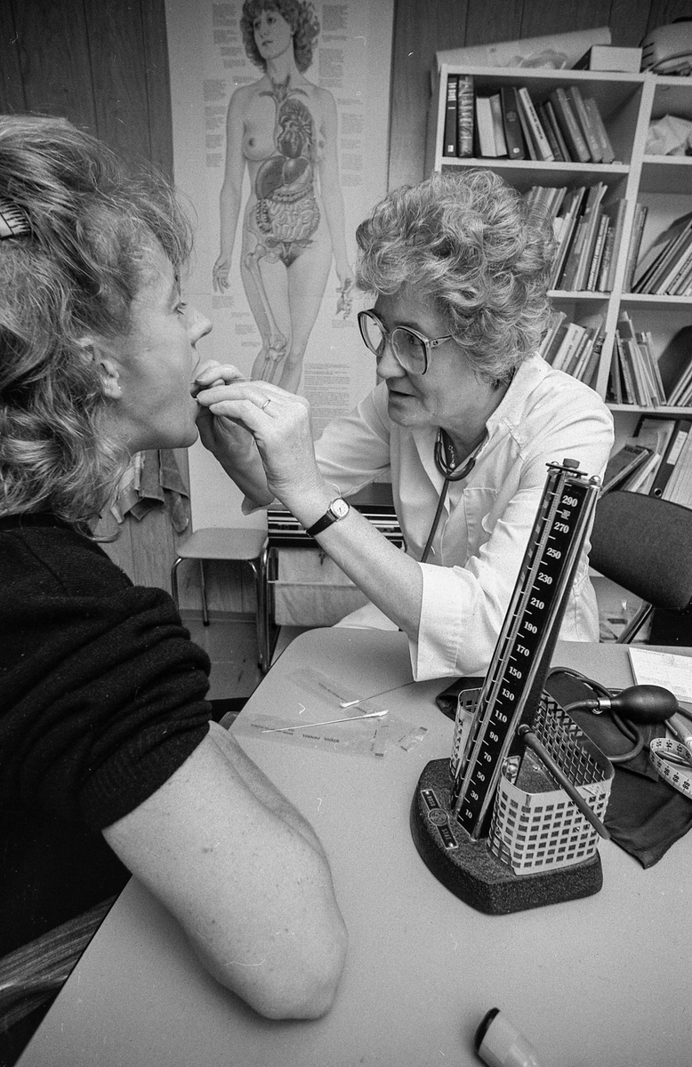 Illustrasjonsfoto. Besøk hos legen, måler blodtrykket og kikker i halsen. Kvinnelig lege og pasient.