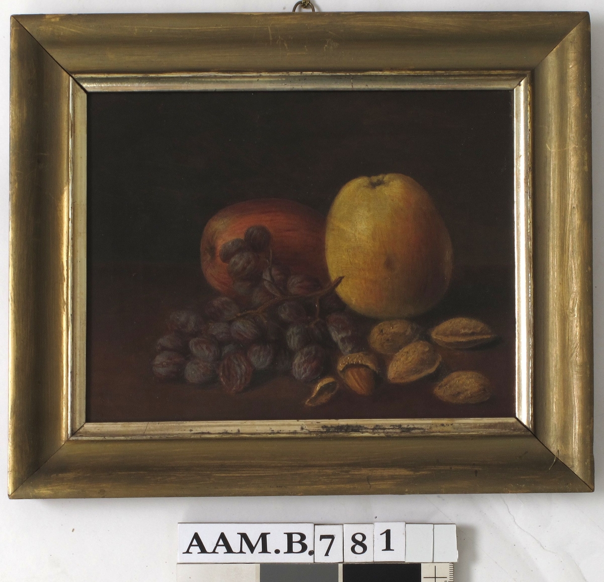 Stilleben, frukt og nøtter. På en brunmalt bordplate ligger 2 epler,en klase rosiner, 5 krakkmandler. Bakgrunn er mørk gråbrun, litt lysere i høyre side.