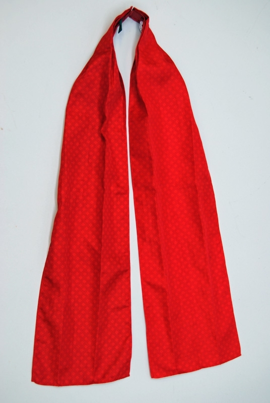Långsmal säkerhetsscarf av rödrutigt polyestertyg med lagda veck mot kardborrfäste i nacken. Märkt med svart lapp med SJ:s logga och tvättanvisningar.

Scarfen tillhör 2008 års uniformsreglemente för SJ.

Modell/Fabrikat/typ: 2008