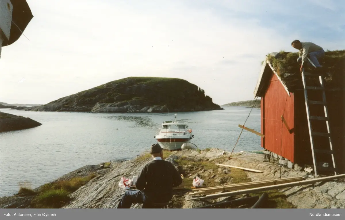 Gildeskål. Fleina. Fleinholman. To personer ved en av buene i Fleinholman, Finn Ø.Antonsen på taket. Båt fortøyd. Holmer bak