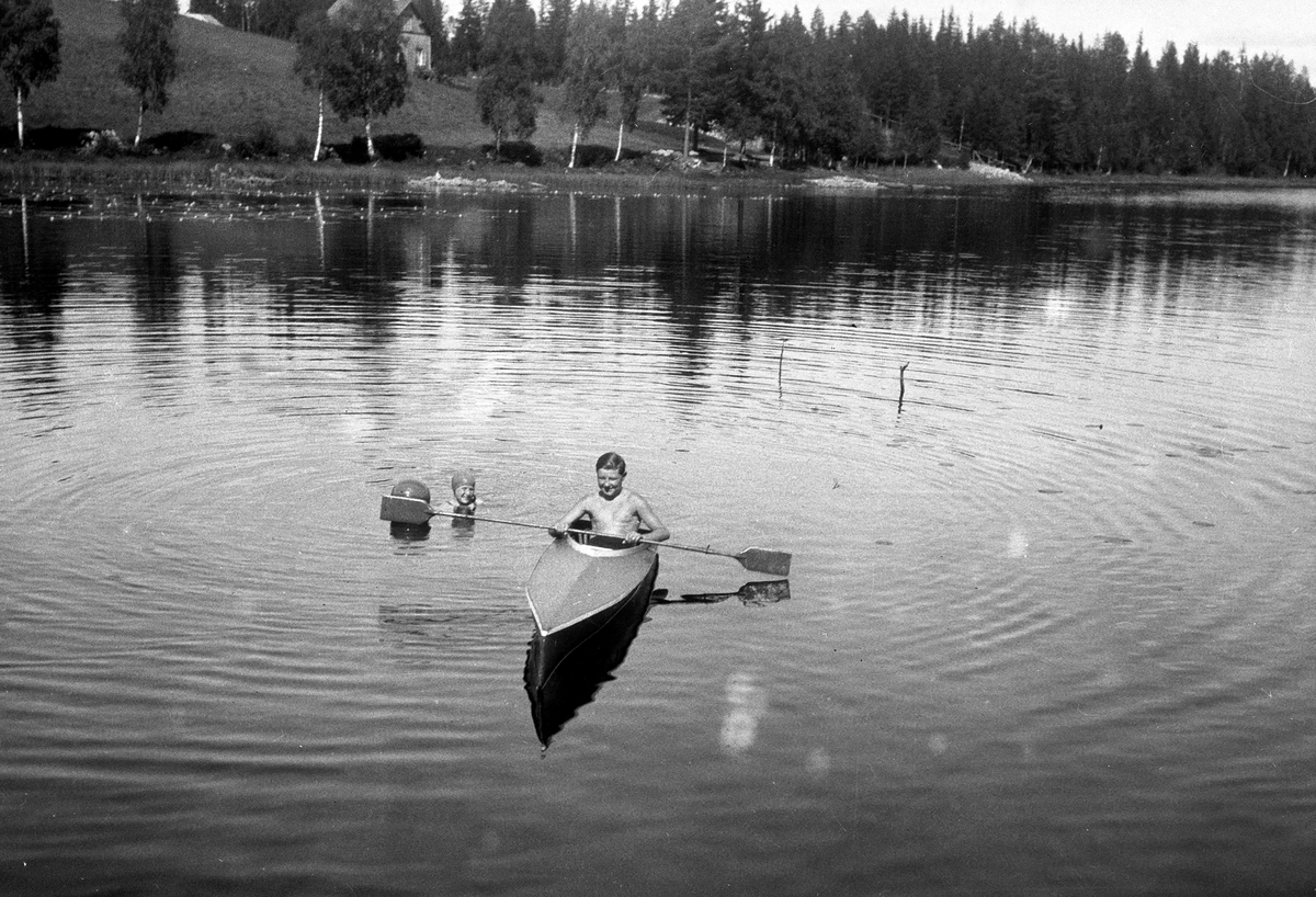 Mann med padleåre i kajakk,Lisjøen.Kvinne med badeball i vann.