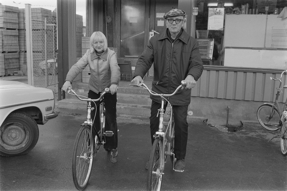 Mann og ungdom på  sykkel utenfor forretning.
Novikveien? I forbindelse med trimløp på sykkel.