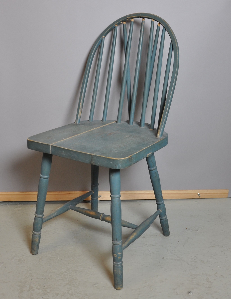 Grønn stol av tre. Setet er sprekt. Spiler i rygg og enkelte sprosser er løse. Bein og sprosser er dreid.
