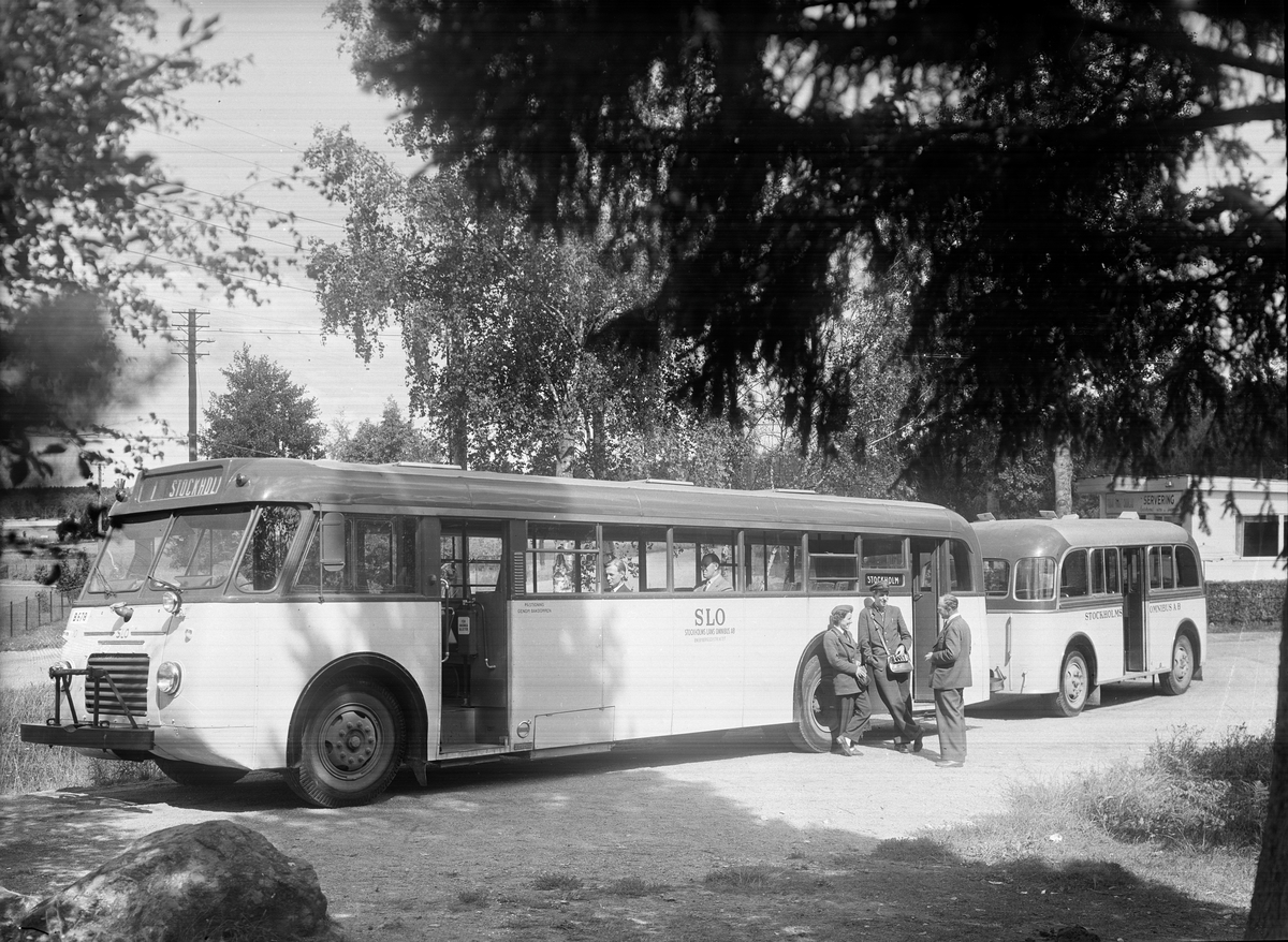 Visinge vändslinga 1951. Buss 10 med släpvagn, från Stockholms Läns Omnibuss aktiebolag SLO.
I sidofönstren syns främst direktör N. E. Nerell, sedan Rolf Wahrenstedt.
Vid sidan av bussen står Laila Sköld, Lasse Kling, och Harry Elsnert.