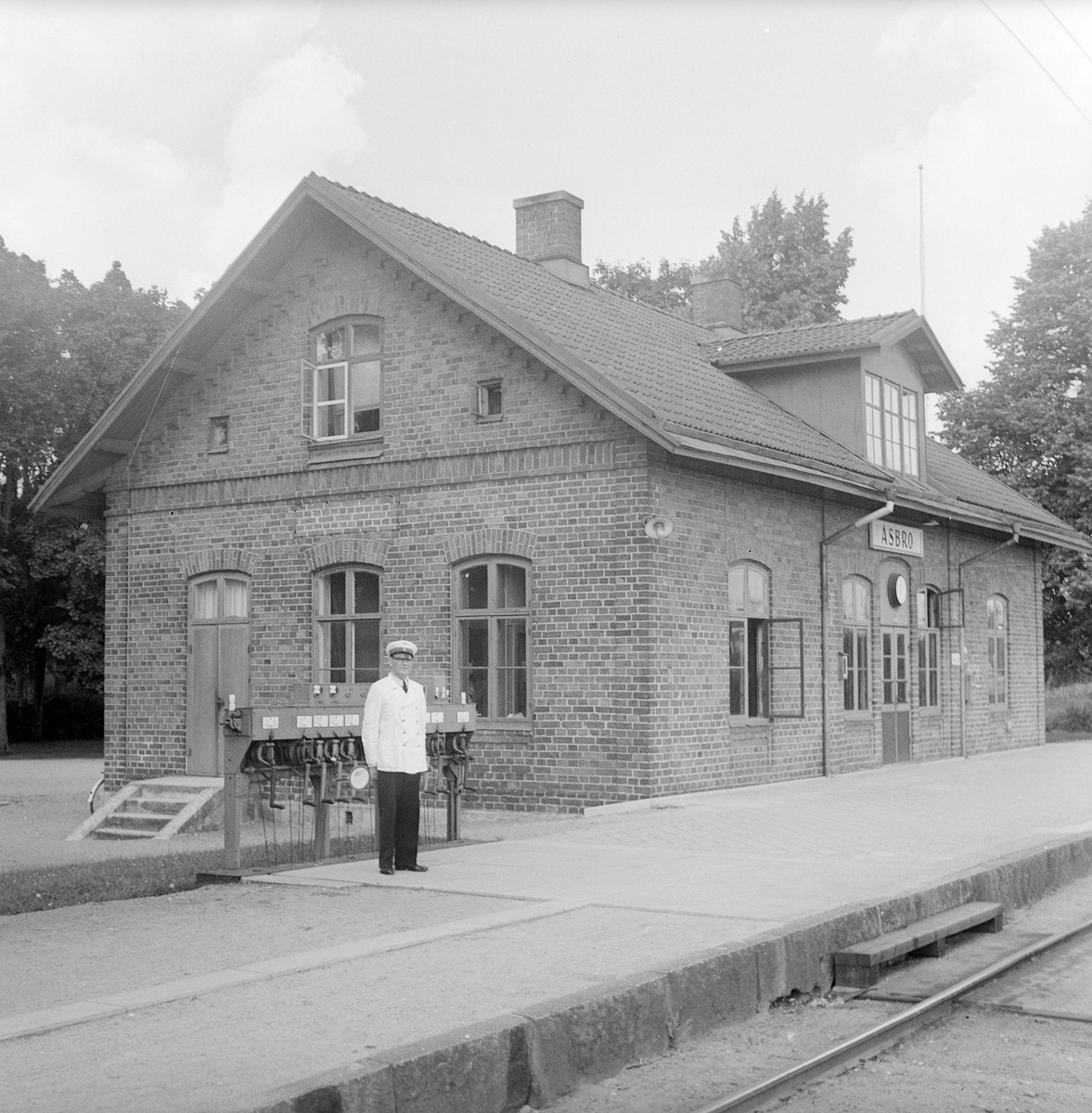 Åsbro station. Trafikplatsen öppnades 1874 av Hallsberg - Motala - Mjölby Järnväg, HMMJ.  Övergick till SJ 1879. På bilden syns tågklarerare med signalstav.
