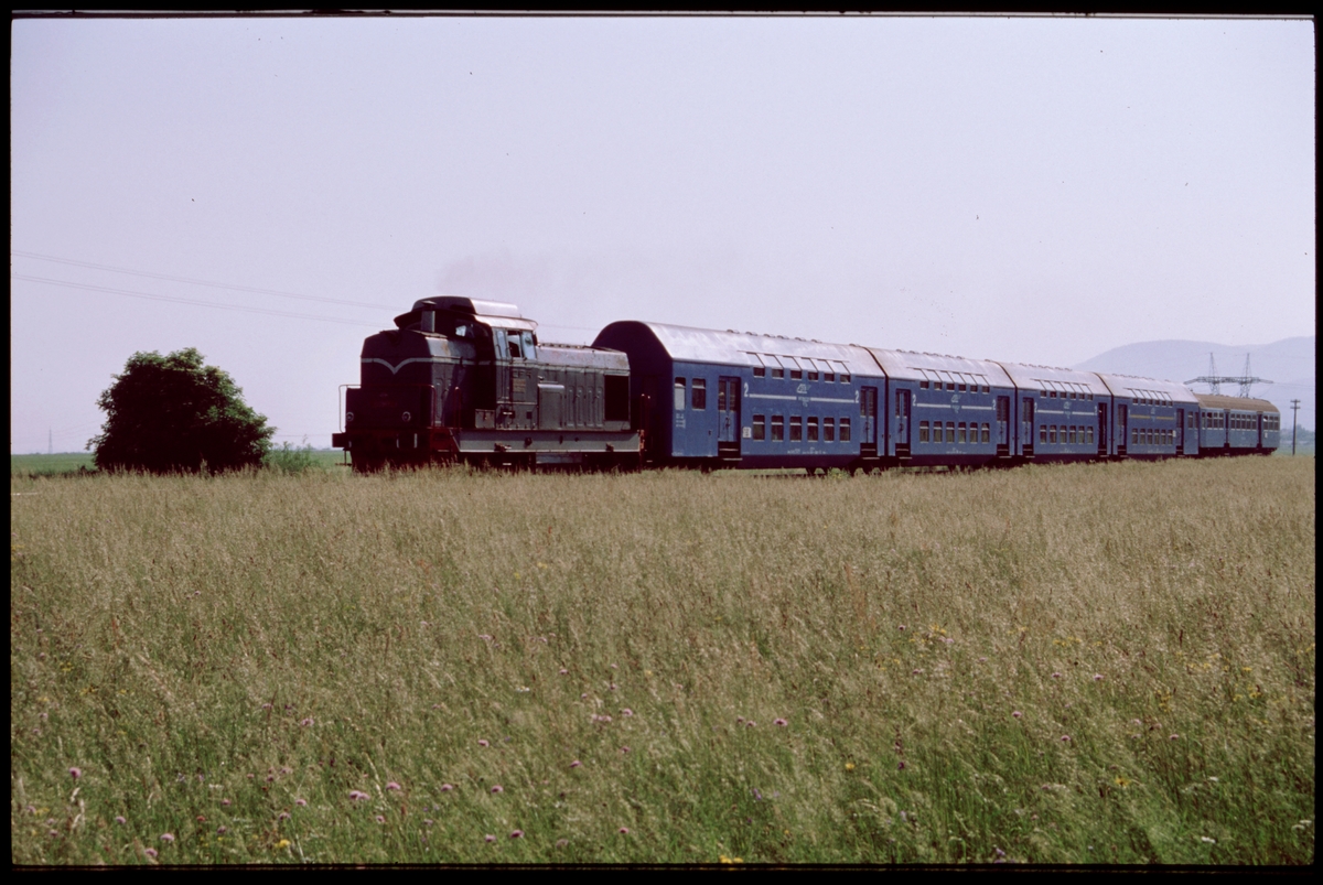 Diesellok typ 80 med personvagnar i riktning mot Zărnești. På sträckan mellan Brașov och Zărnești, Rumänien.