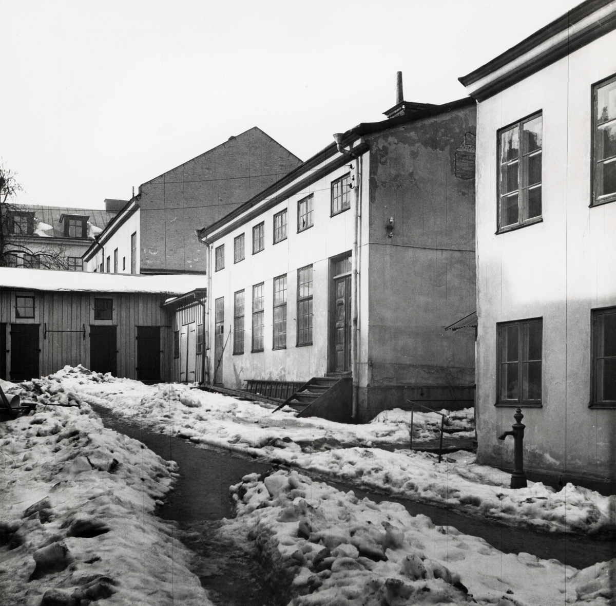 Gårdsinteriör tillhörande Tunnbindaregatan 19 i kvarteret Haken, Norrköping. Bilden är tagen i samband med rivningsansökan 1953. John Journath Byggnadsbyrå kommer under 1950-talet bygga nya bostäder inom kvarteret med början på tomten Haken nr 9. Vy mot norr.