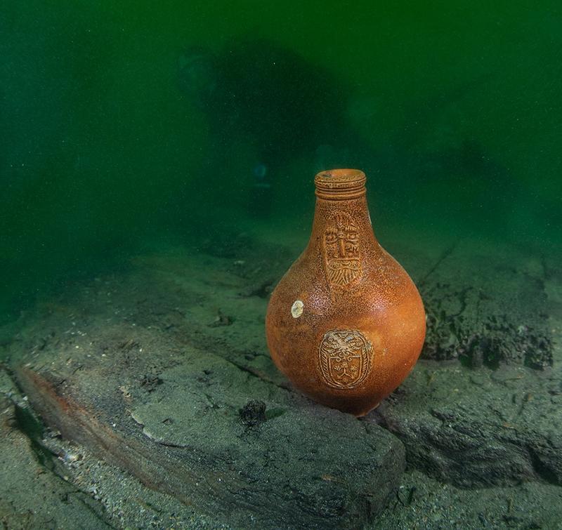 Bartmannskrukke i oransje keramikk, fra siste halvdel av 1600-tallet, står på bunnen blant båtdeler fra vraket av Pelikanen. (Foto/Photo)