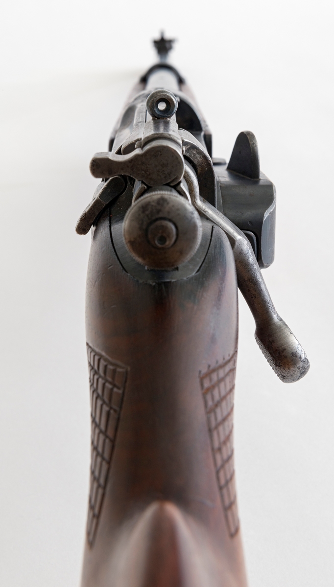 Riflegevær av Krag-Jørgensen-type, antakelig produsert ved Kongsberg våpenfabrikk i 1916.  Våpenet er 101 centimeter langt, hvorav stokken er 78, 8 centimeter.  Største bredde (11, 8 centimeter) er målt ved enden av kolba, der det later til å ha sittet et kappebeslag, som ikke er intakt.  Beslaget er borte, men utsparinger og skruehull tyder på at geværkolba har hatt en slik forsterkning i enden.  Kolba har ovalt tverrsnitt og glattpusset overflate.  Ved kolbehalsen er det en markert forsenkning på oversida og en markert knopp på undersida.  Foran er det rombeformete, skraverte felt på begge sider av stokken.  På den fremre delen av stokken er det hulkilformete forsenkninger i lengderetninger, som sannsynligvis skulle gi brukeren et godt venstrehandsgrep om våpenet.  Geværet har hatt bærereim, som har vært festet i ei bøyle på undersida av kolben og i beslaget som forbinder den fremre delen av stokken og løpet.  Et hull på undersida av og på tvers av kolben er spunset med treplugger.  Våpenet har en magasinbrønn for patroner på høyre side.  Bakerst på sluttstykket er det en knast, som når den vendes mot høyre, låser våpenet.  Med unntak av det nevnte beslaget rundt fremdre del av stokken og løpet, som er merket «129», er både stokken og stålkomponentene stemplet «951», noe som betyr at våpenet stort sett består av originaldeler.  Siktet er imidlertid ikke originalt (jfr. gjengitt brev fra giveren under fanen «Historikk»).  Her er det montert et stolpesikte foran og et dioptersikte bak.  Produksjonsåret 1916 er påstemplet i forkant av sluttstykket, under Kongsberg våpenfabrikks monogram. 