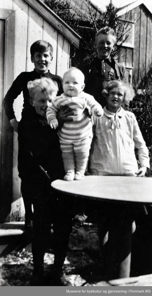 Nordvågen. Fem barn i hagen på Holmen. I bakgrunnen lekehuset og vaskehuset. 1929.