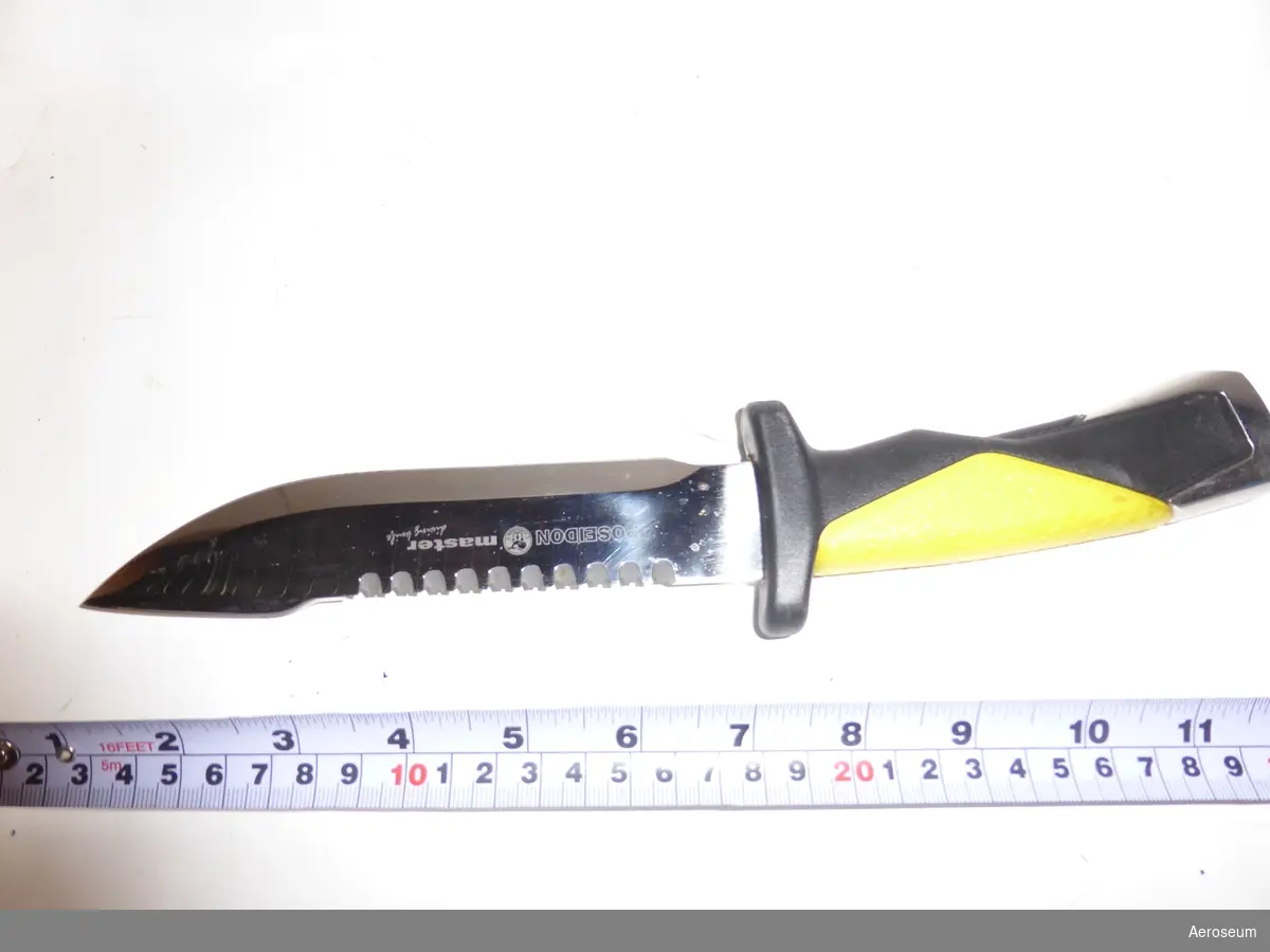 En dykarkniv i rostfritt stål med plastskida och gulsvart handtag.
På skidan står det "Aitor".