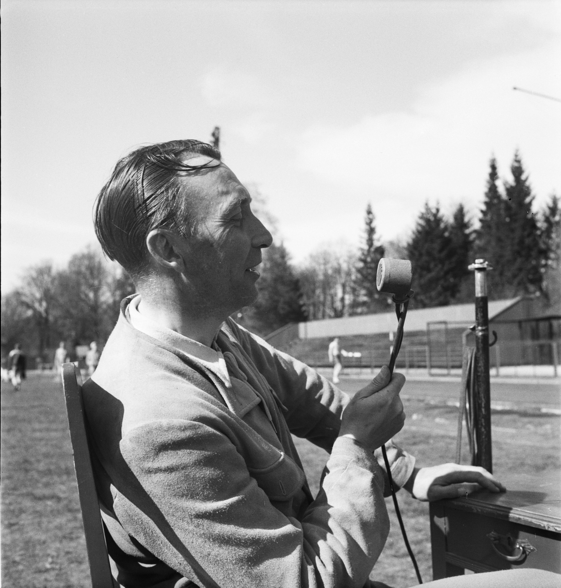 Idrottsinstruktör Bertil Åström sittandes utomhus med mikrofon, Uppsala