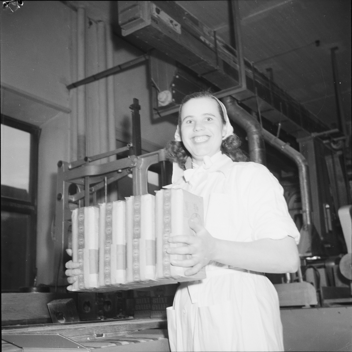 Arbetande kvinna bär paket, 75-årsjubileum, Upsala Ångqvarns AB, Uppsala 1949