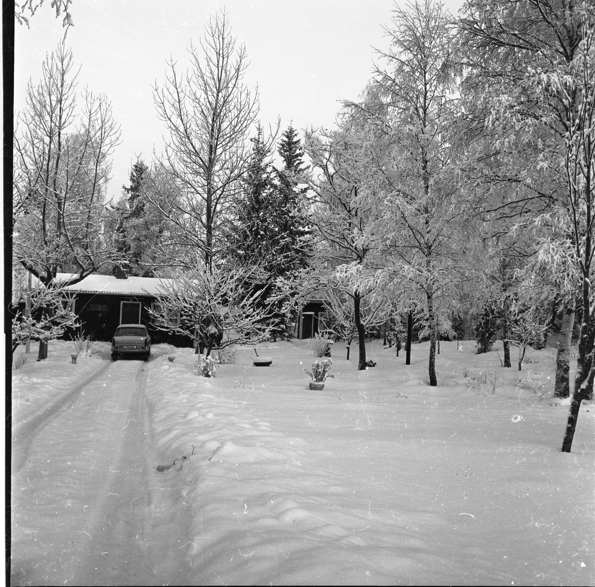 Vinterlandskap. En bil står uppkörd vid ett litet hus med en skylt "Haga". Möjligen i trakterna kring Örserum.