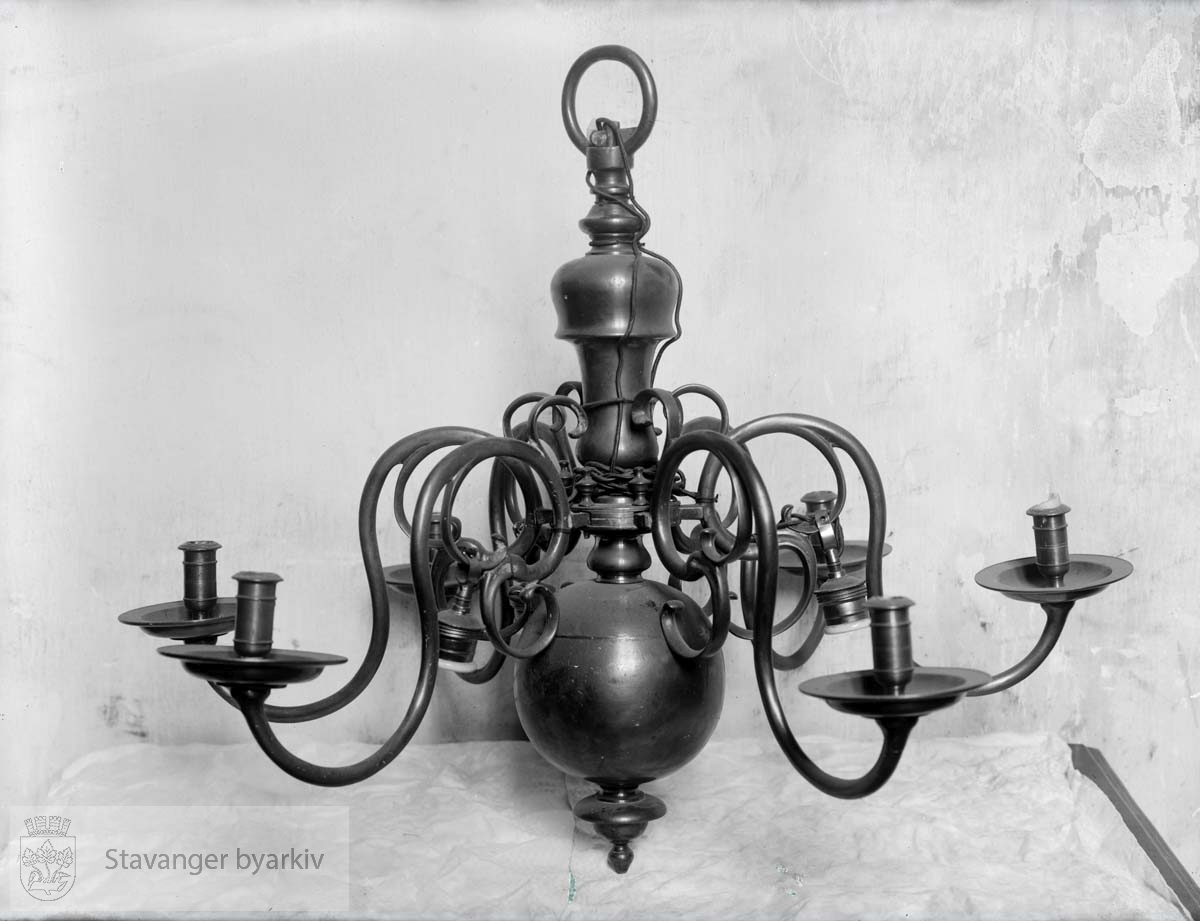 Lysekrone for stearinlys. .Ble byttet ut med Emmanuel Vigelands lysekroner i 1923.