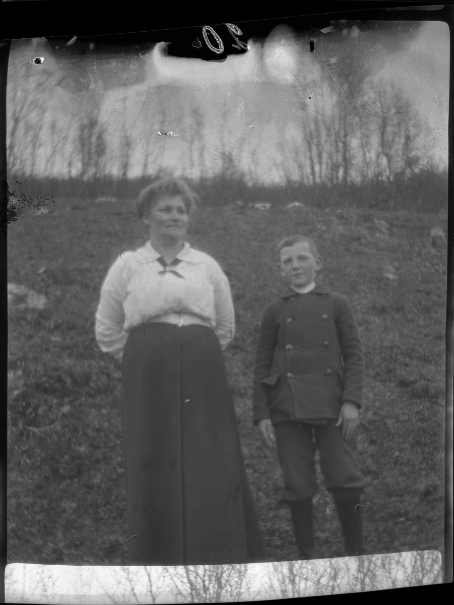 Portrett av en kvinne og en gutt, fotografert stående utendørs.