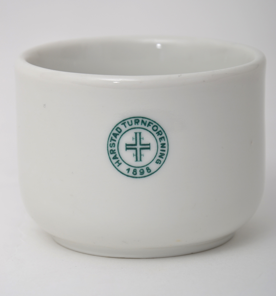 Hvit kaffekopp, med turnforeningens grønne logo.