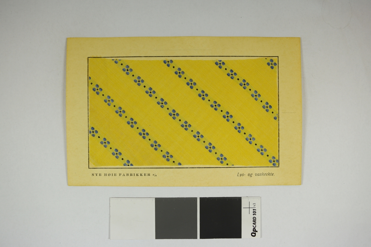 Prøvekort bestående av tekstilprøve limet til et papirkort. Prikkete mønster.
