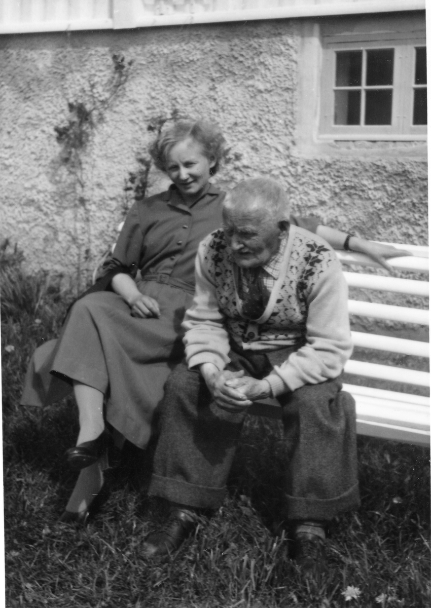 Ung dame og eldre mann sittende på hvitmalt benk