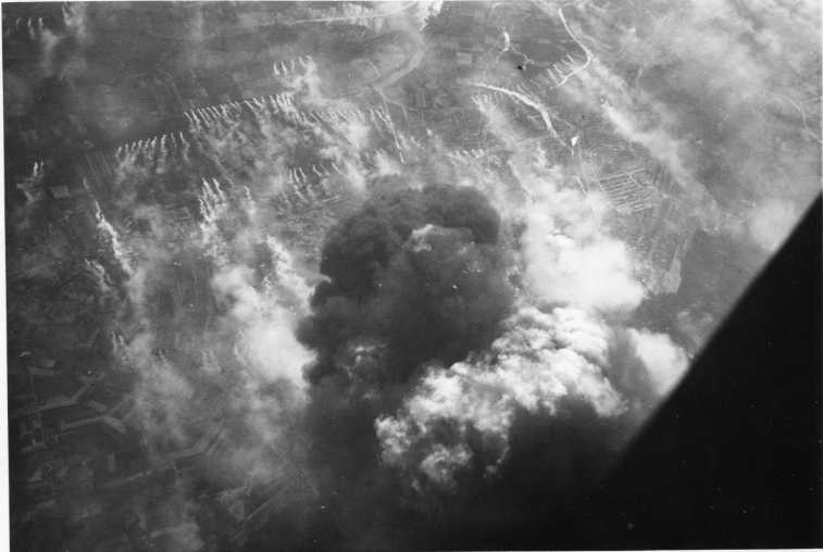 Bomber faller över Tyskland. Kraftig rök på marken och i luften.