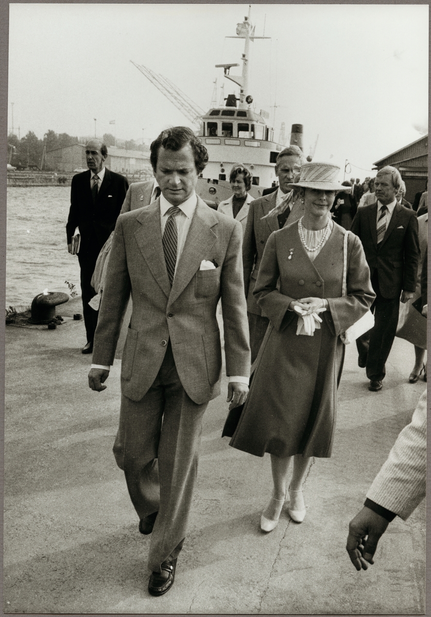 Kung Carl den XVl Gustaf och Drottning Silvia i Oxelösunds hamn den 9 september 1980. Trafikaktiebolaget Grängesberg - Oxelösunds Järnvägar, TGOJ:s bogserbåt "Simson" ses i bakgrunden.