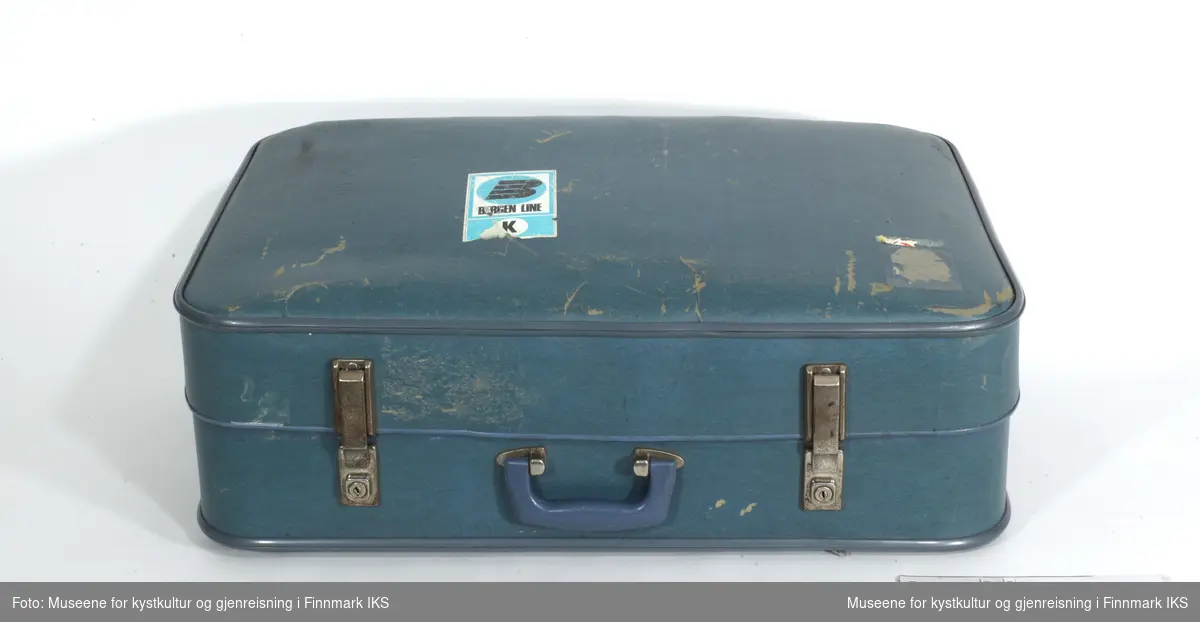 Kofferten består av blå kunststoff og har avrundede kanter som er avstivet med metall, både på lokk og bunn. Den har hengsler og lås av metall. På lokket befinner det seg et klistremerke i blått hvit og svart med påskriften "B-Bergen Line-K". Innsiden av kofferten er utkledd med papir med brunrutet mønster med blå og hvite striper.