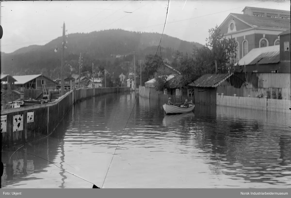 Flom i Tinnesgata i 1927. To menn i robåt i gata mellom husene.