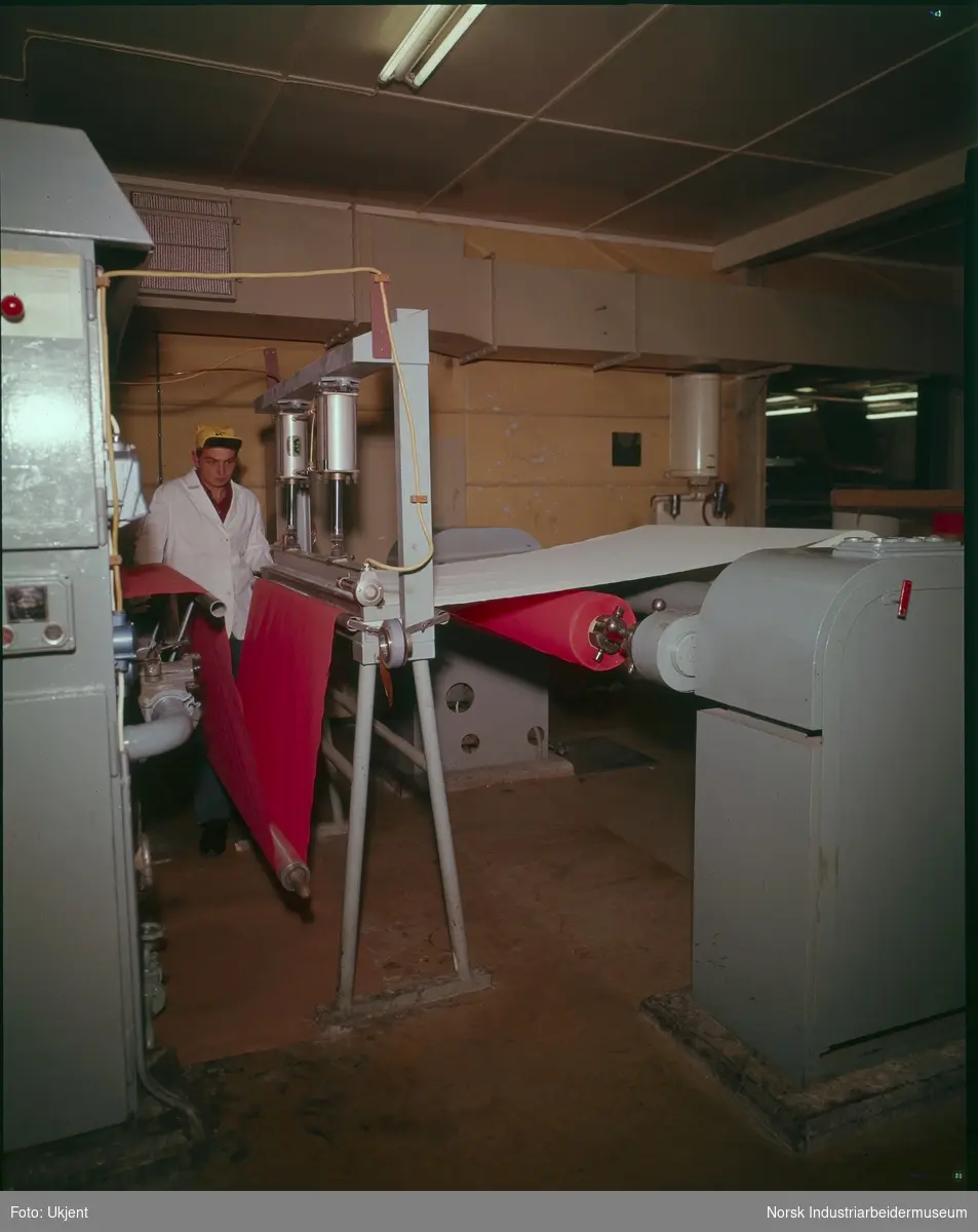 Interiør på Laminatfabrikken. Mann i arbeid ved maskiner.