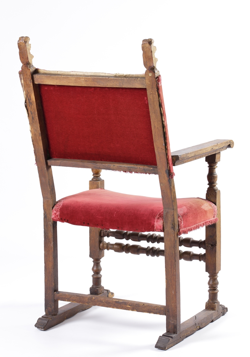 Karmstol av renässansmodell. 
Trästomme med svarvade detaljer. Sits och rygg klädda med vinröd sammet, kantad med brokadband i samma färg, med bladdekor.
