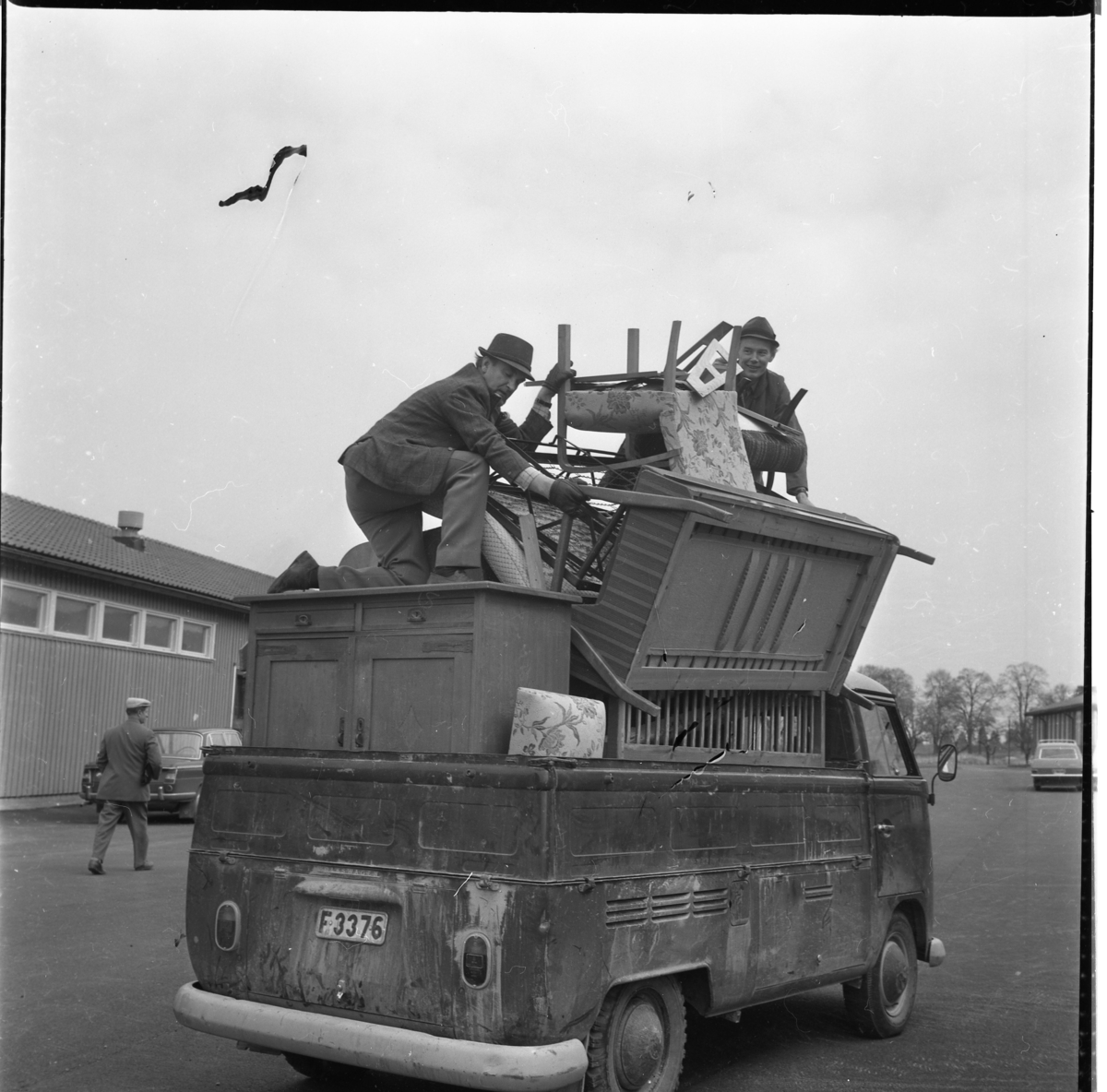 En Volkswagen pickup fullt lastad med olika möbler och högst upp två män som packar.