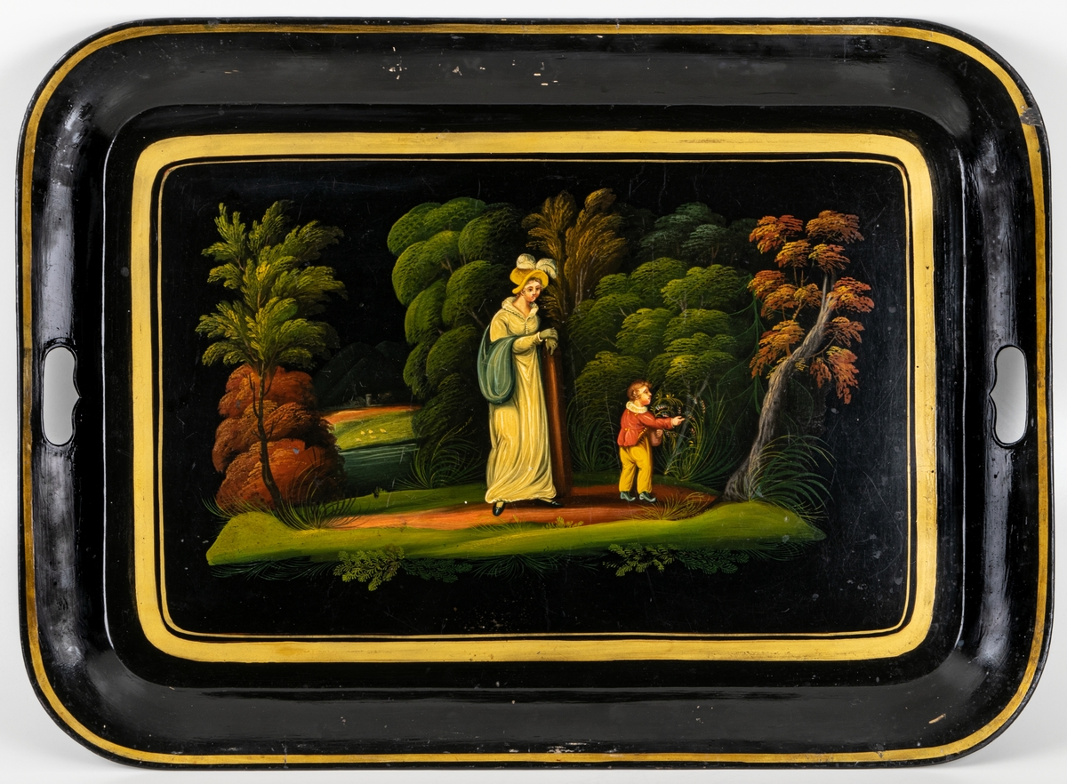 Bricka av svartlackerad plåt, målad med figurer i landskap,fyrkantig 1820-tal.
Fyrsidig med rundade hörn. Handtag urtagna i kortsidornas bräm. Svart bild i grönt, gult, rött mm. Inom guldram: kvinna och pojke mot bakgrund av träd mm. Dräkterna tidigt 1800-tal.