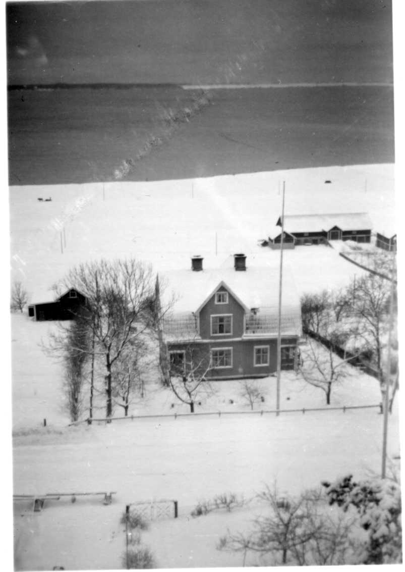 En vy från Grännaberget, vintertid, ned mot bland annat ladugård tillhörande "Johan på gärdet".