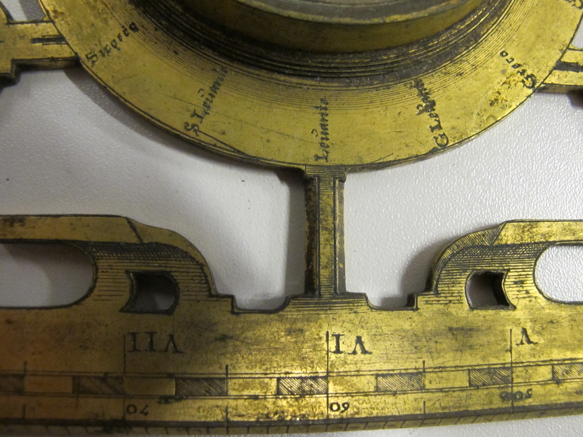 Diopterlinjal av förgylld koppar med bredvidliggande kompass i koppar. Italiensk och delvis holländsk text på linjalen med siktdiopter och likformig skala med 120 enheter.