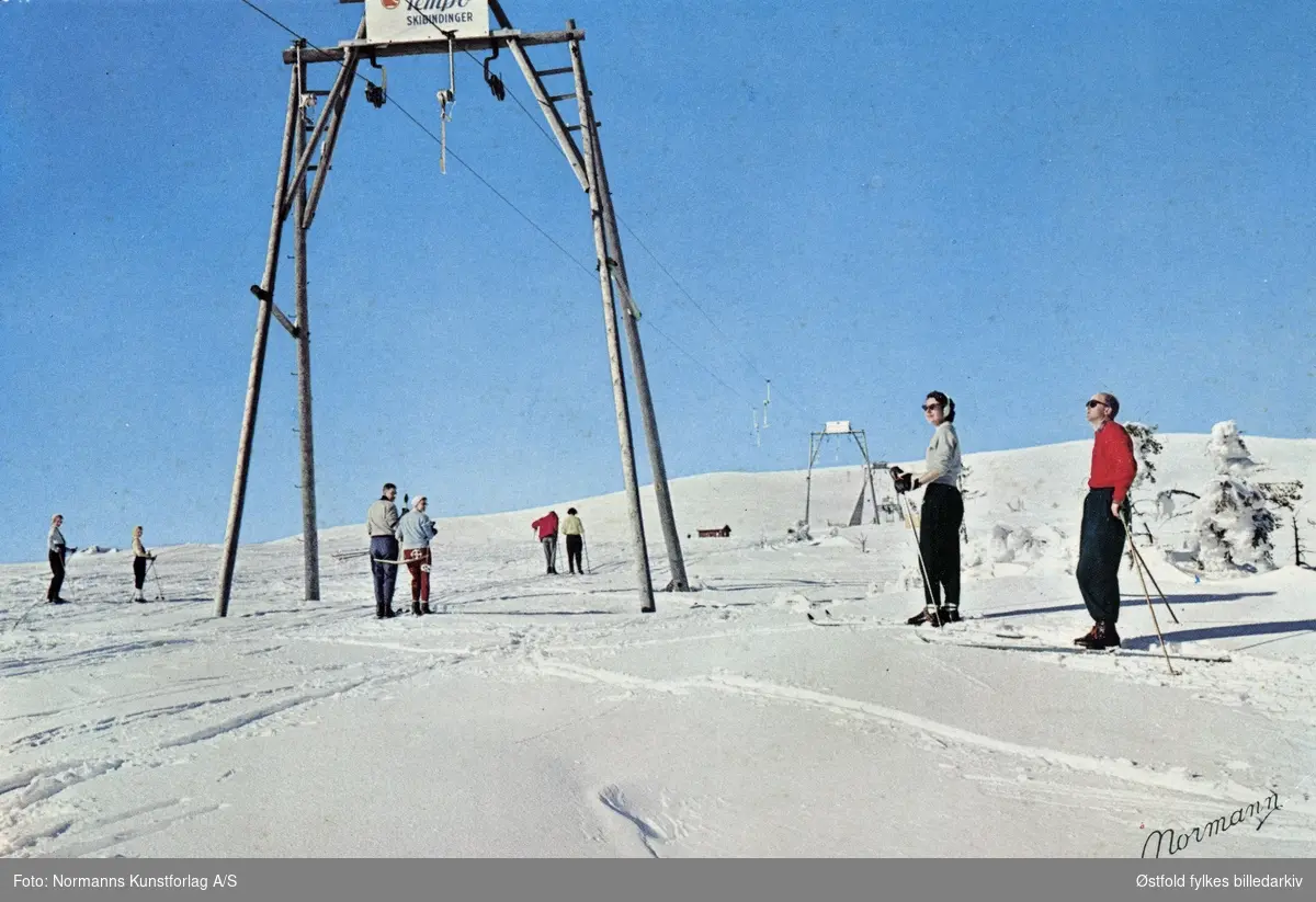 Skihei osg skiløpere på høyfjellet i Norge, ukjent sted. Postkort u.å. Reklameskilt for Tempo skibindinger.