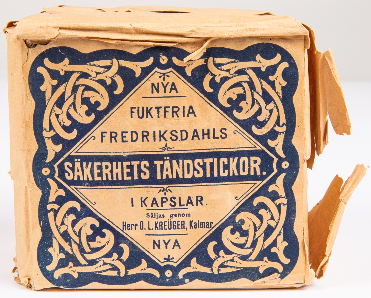 Kat.kort:
Tändstickor, etikett: "Nya fuktfria Fredriksdahls Säkerhets Tändstickor. I kapslar. Säljas genom Herr O. L. Kreüger, Kalmar."
(Blått tryck på vit botten)

1 större förpackning och 4 små förpackningar.