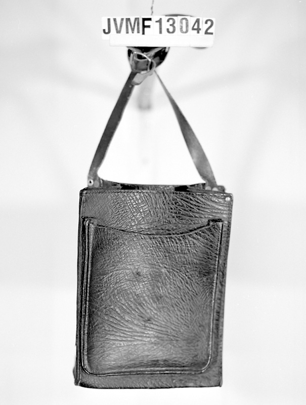 Väska av brunt präglat läder, med rem. Ett fack framtill, och flera mindre fack inuti.