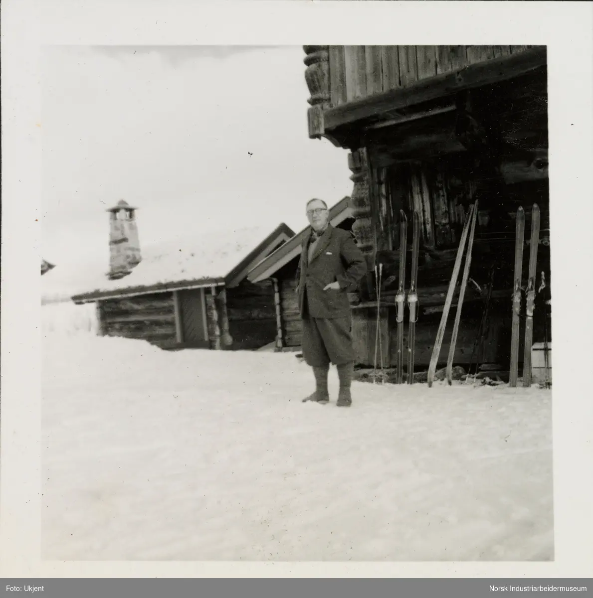 James Coward står i snøen på hyttetun på Sundet, Møsstrond. Loft med ski stablet langs vegg