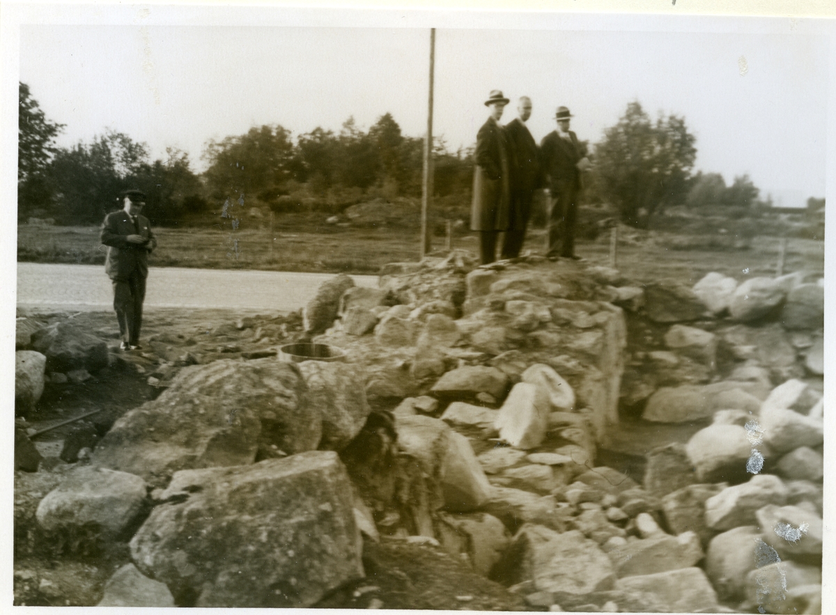 S:ta Gertruds kapell vid Hammarby Sjöhage i Västerås.
Tre män står på stenmuren och en man står nedanför.