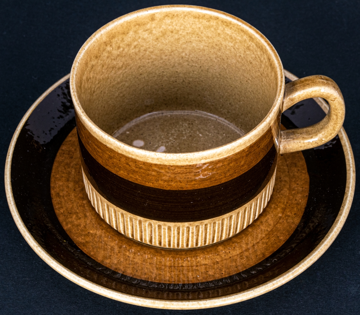 Kaffekopp modell EH, dekor Terra, modell och dekor av formgivare Berit Ternell. Gulbrun glasyr med ljusbrunt och mörkbrunt band.