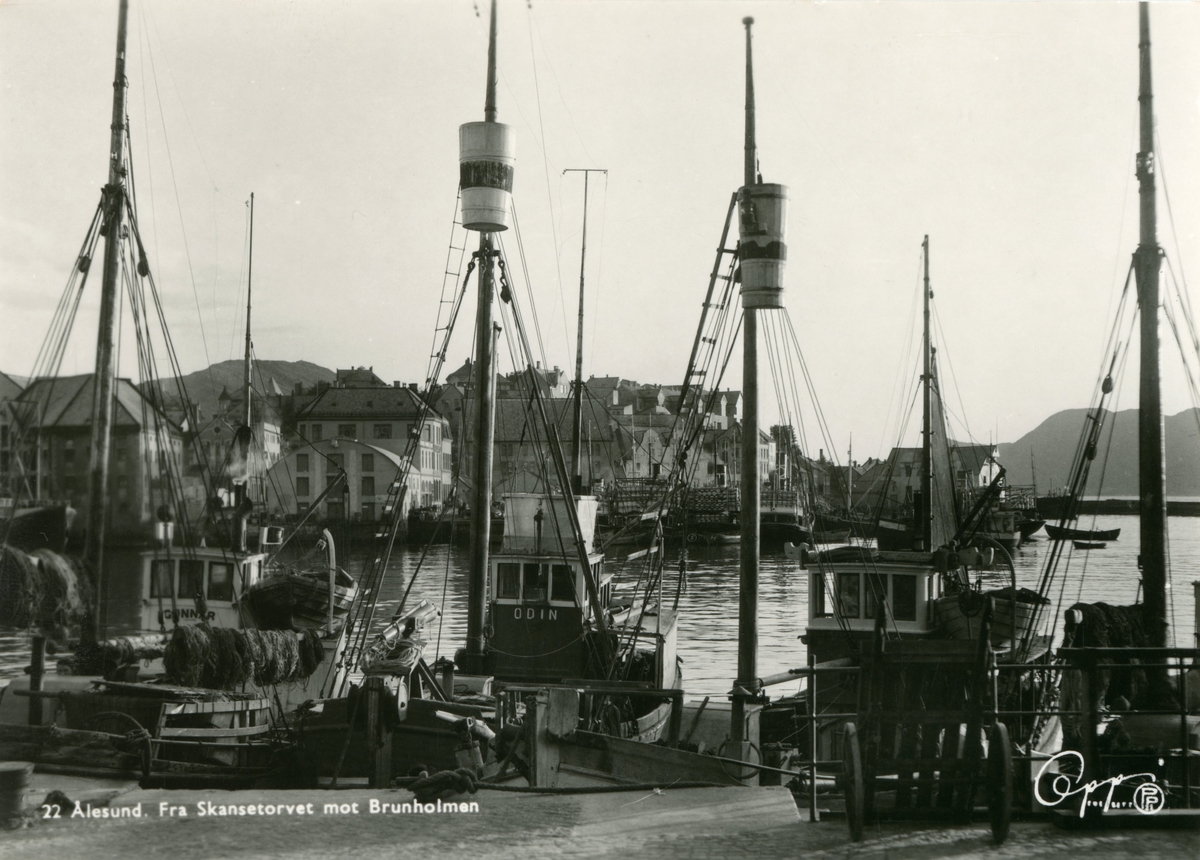 Motiv av ei rekke fiskebåter ved kai i Ålesund havn. I bakgrunnen ses Brunholmen. To av båtene viser navnene "Odin" og "Gunnar".